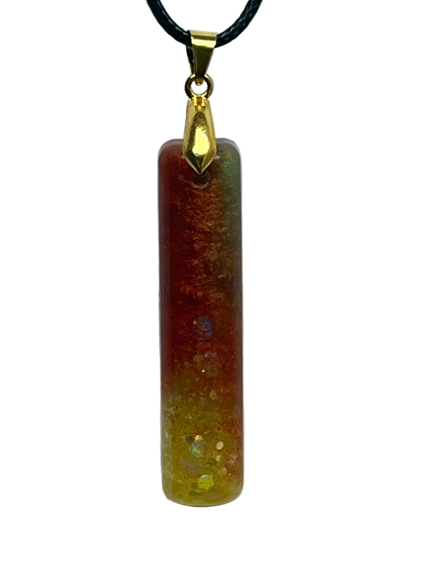 A slender vertical bar-shaped resin pendant with a gradient from deep ember-red and amber at the top to golden-yellow at the base, scattered throughout with iridescent opal flecks that flash green, blue, and white. It hangs from a gold-toned bail on a black braided cord against a pale background.