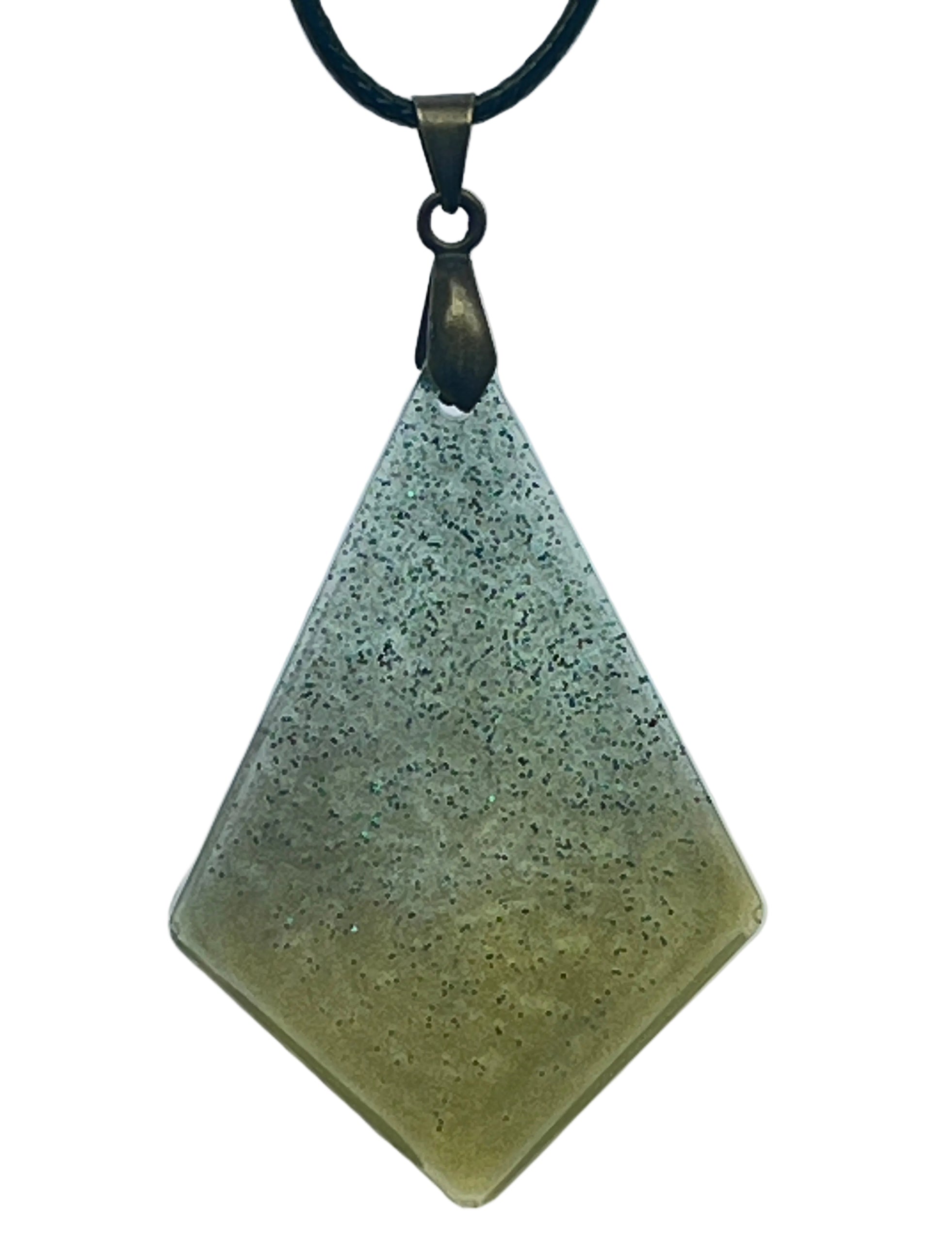 A kite-shaped (elongated diamond) resin pendant with a gradient from cool sage-grey at the top to warm olive-green at the base, scattered throughout with fine dark green glitter. It hangs from an antiqued brass bail on a black braided cord against a pale background.