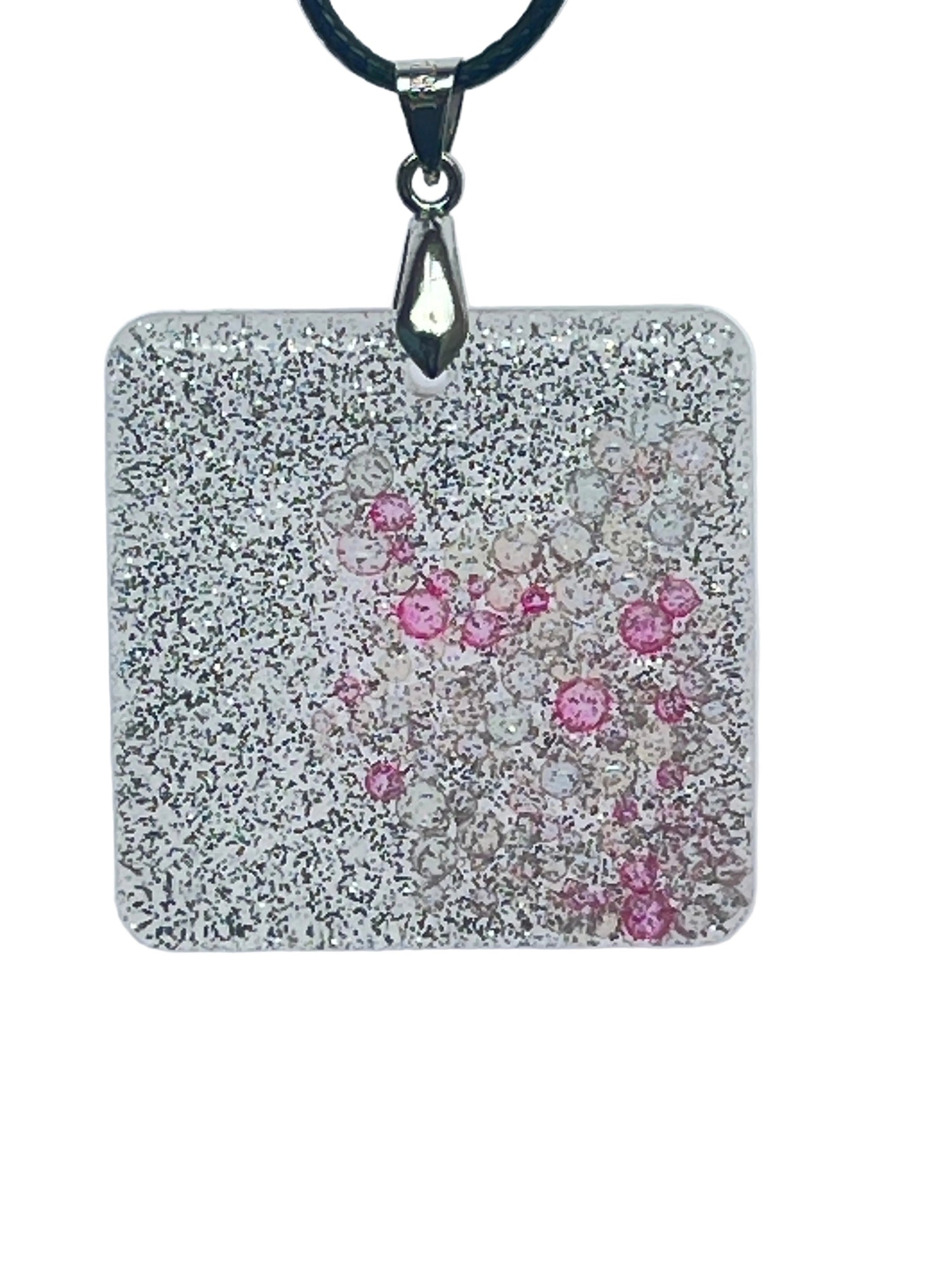 A square-shaped resin pendant densely covered in fine silver glitter, with a cluster of clear and rose-pink bubble-bead inclusions drifting near the center. It hangs from a silver-toned bail on a black braided cord against a pale background.