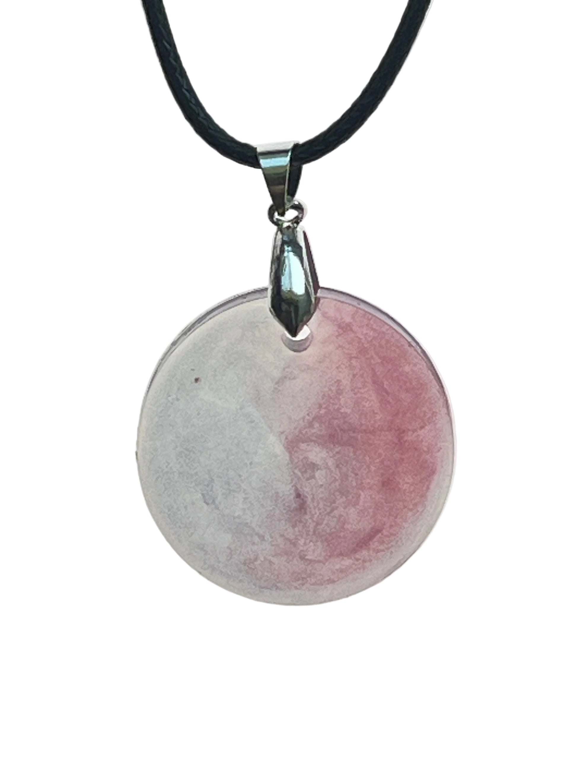 A round disc-shaped resin pendant split between a soft misty grey-white half and a dusty rose-mauve half, meeting in a clean line down the center. It hangs from a gunmetal bail on a black braided cord against a pale background.