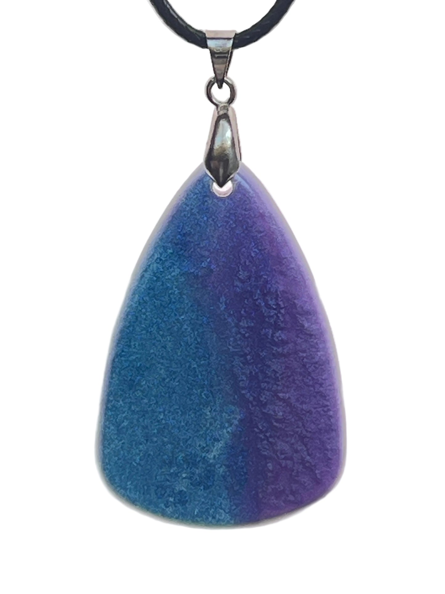 An organic, rounded triangular-shaped resin pendant with a gradient blending teal-blue on one side into deep violet and indigo on the other. It hangs from a silver-toned bail on a black braided cord against a pale background.