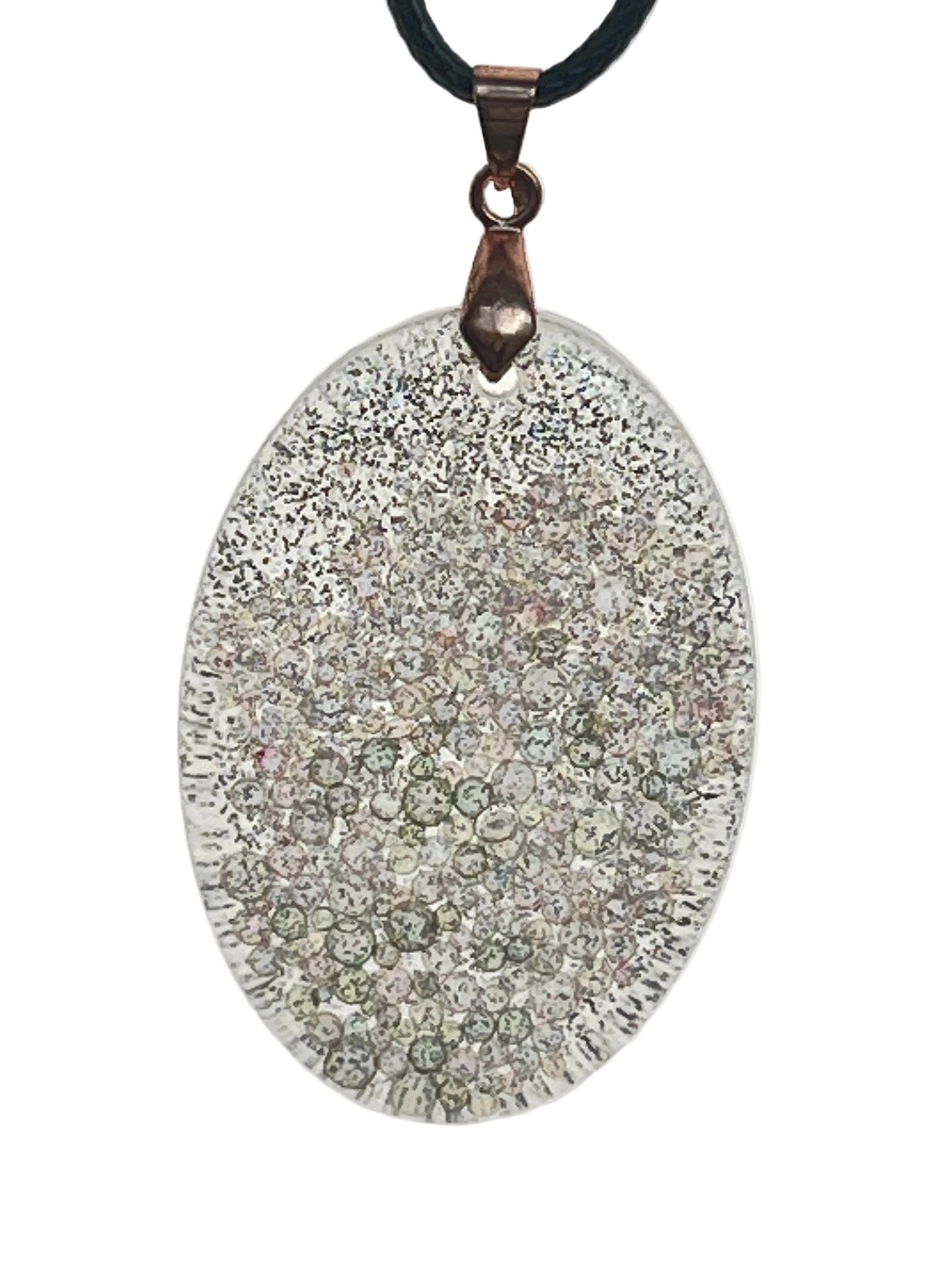A large oval-shaped resin pendant covered in fine frosted white glitter, with a cluster of sage-green and pearl bubble-bead inclusions gathered toward the lower half, and a ribbed textured edge. It hangs from an antiqued copper bail on a black braided cord against a pale background.