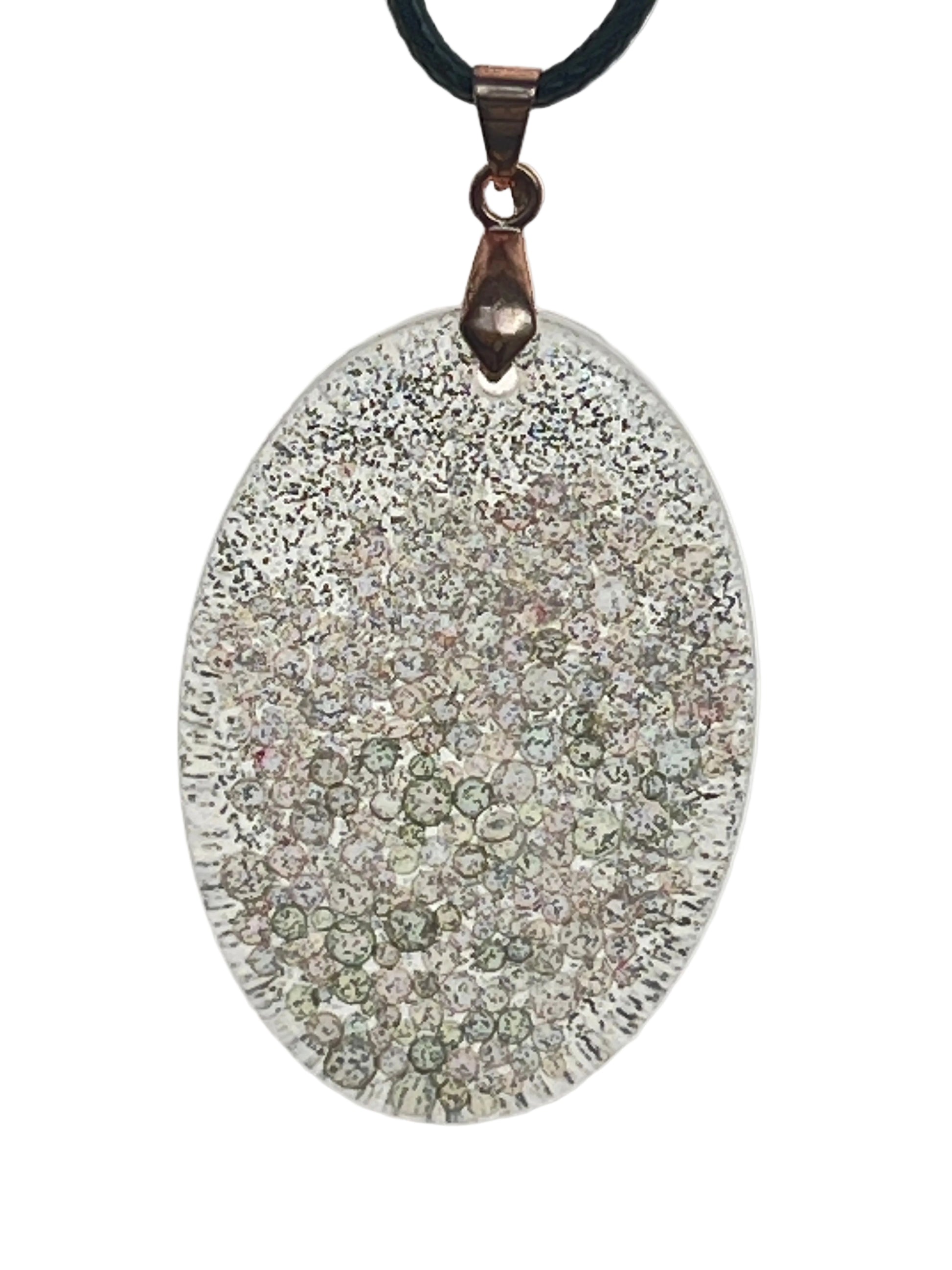 A large oval-shaped resin pendant covered in fine frosted white glitter, with a cluster of sage-green and pearl bubble-bead inclusions gathered toward the lower half, and a ribbed textured edge. It hangs from an antiqued copper bail on a black braided cord against a pale background.