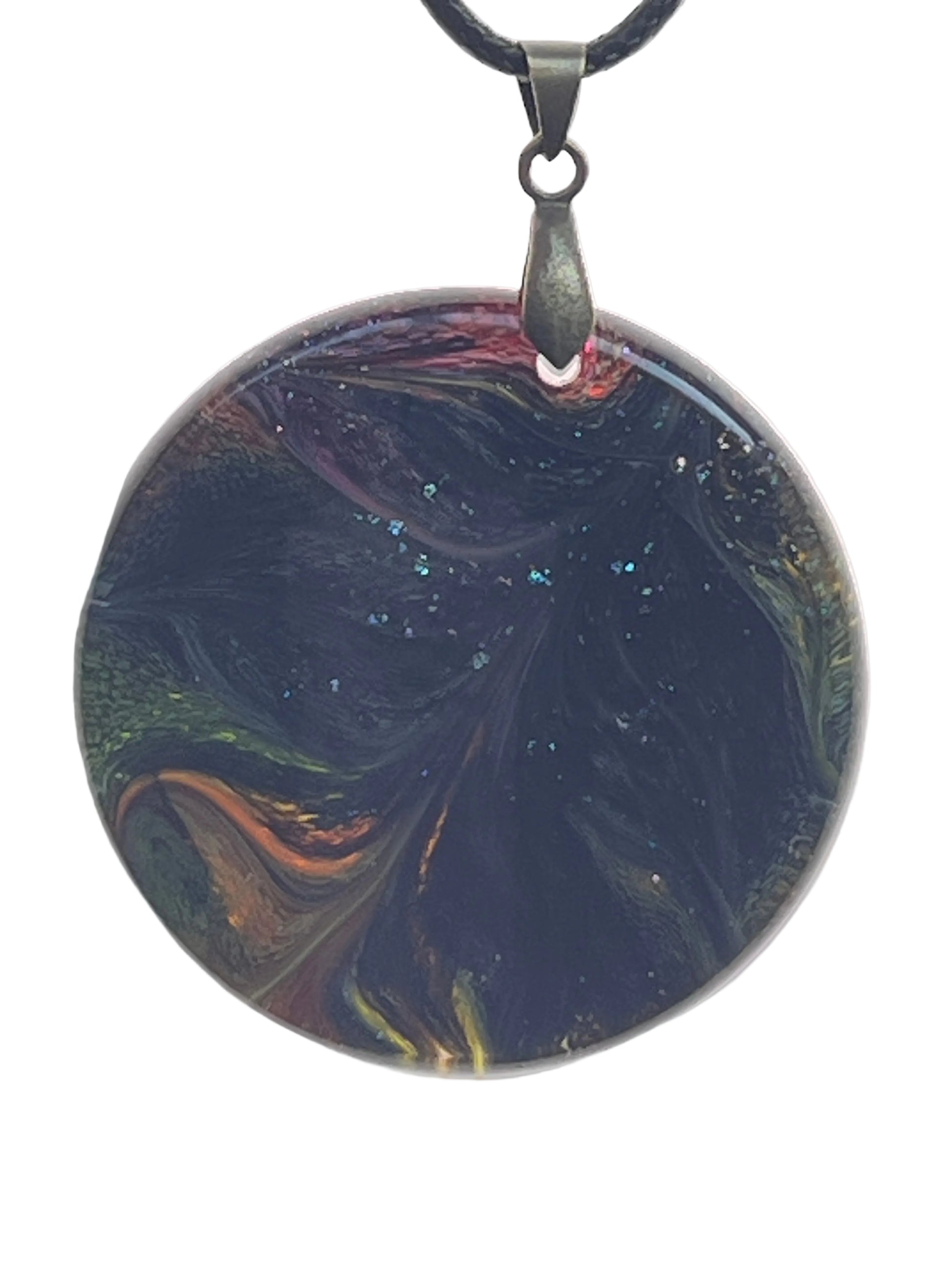 A large round resin pendant with a deep, swirling near-black base dusted with fine glitter, and glimpses of amber, orange, crimson, and jade green along the edges. It hangs from a gunmetal bail on a black braided cord against a pale background.